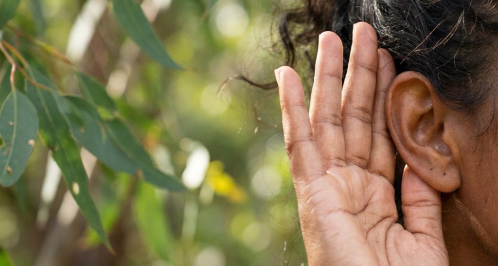 Australian person listening hand to ear for world mental health day